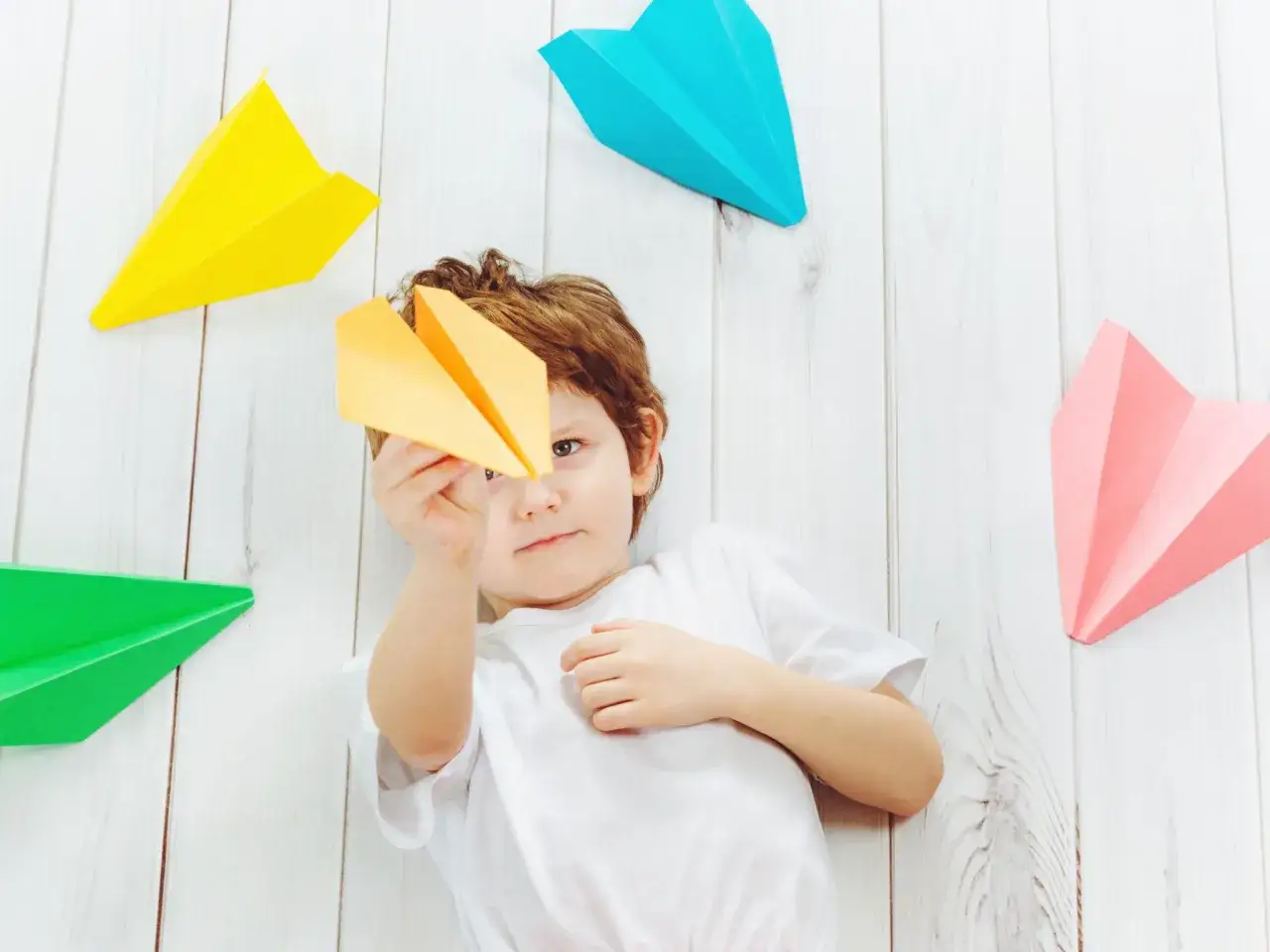Ni&ntilde;o jugando con aviones de papel de colores, resultado de divertidas avion manualidades.