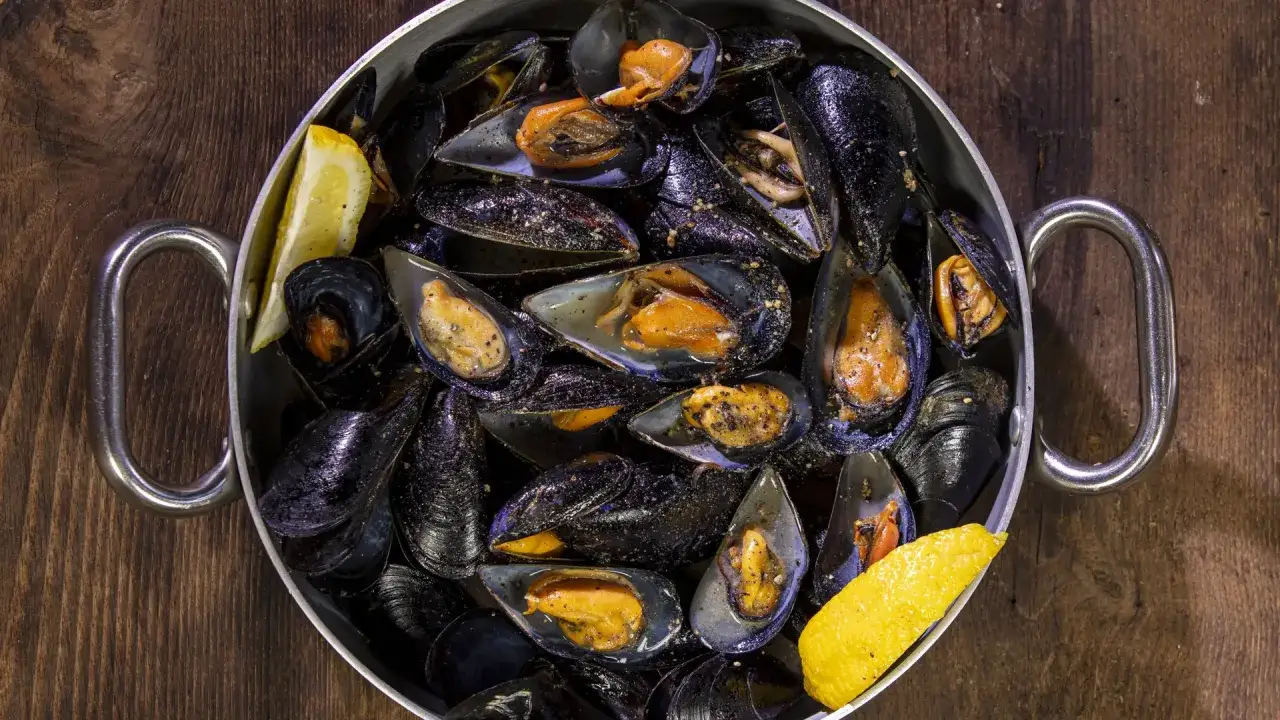 ImPEPata di cozze fumante in pentola, con spicchi di limone, pronta per essere gustata.