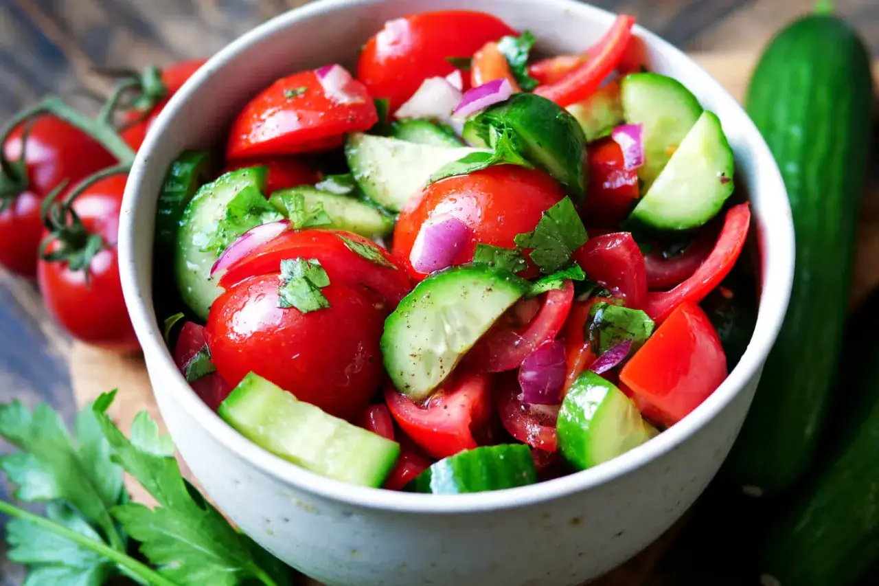 Frischer Tomaten-Gurken-Salat mit roten Zwiebeln und Petersilie, garniert mit ganzen Tomaten und Gurken.
