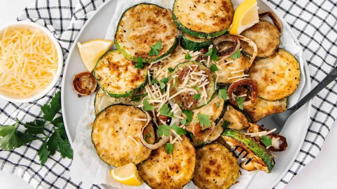 D&eacute;licieuse recette de courgette au four, dor&eacute;e et garnie de fromage r&acirc;p&eacute; et de persil frais. Servie avec des quartiers de citron.