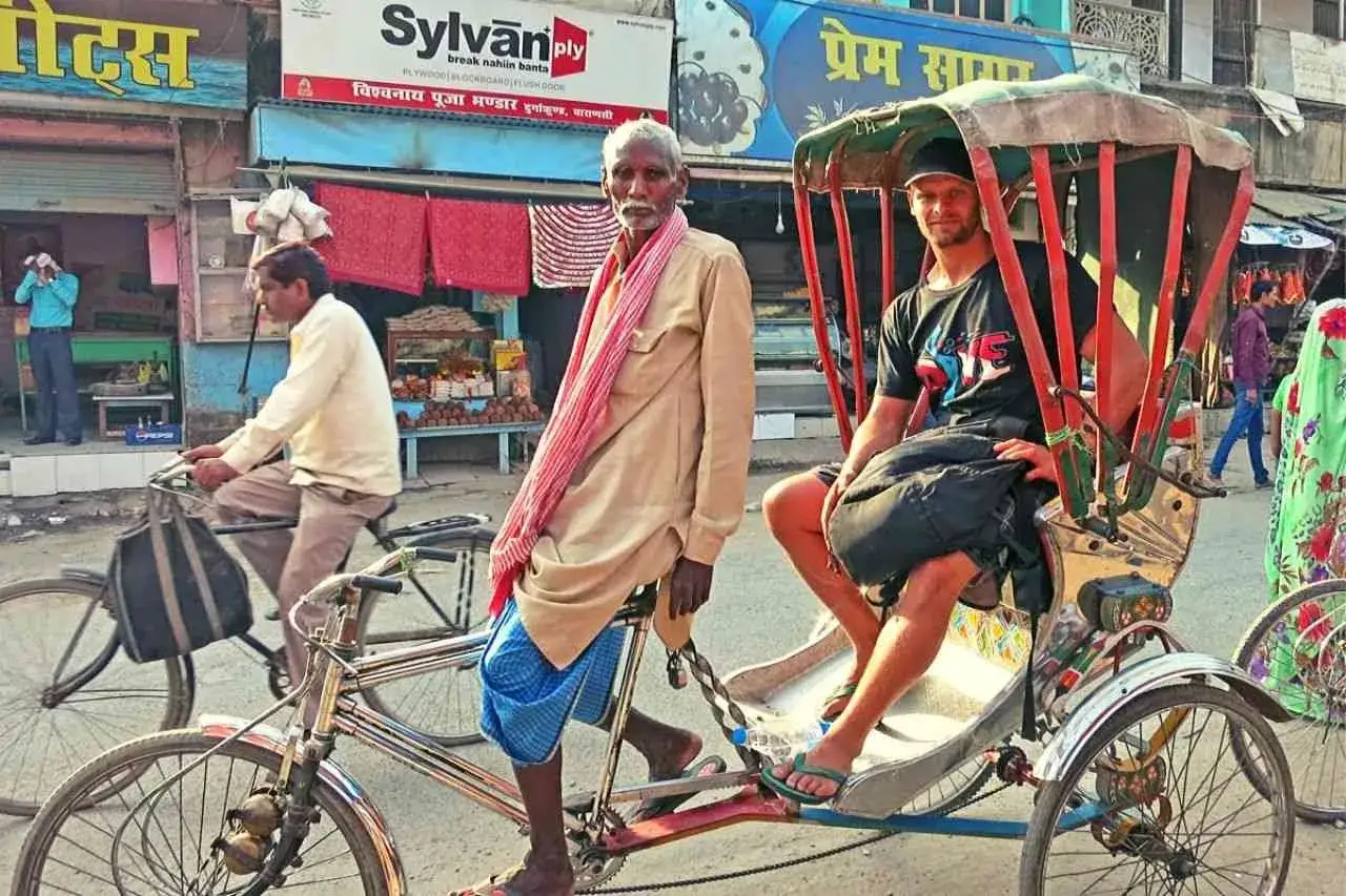 Rowerzysta ciągnie rikszę z pasażerem, typowy transport w Indiach.