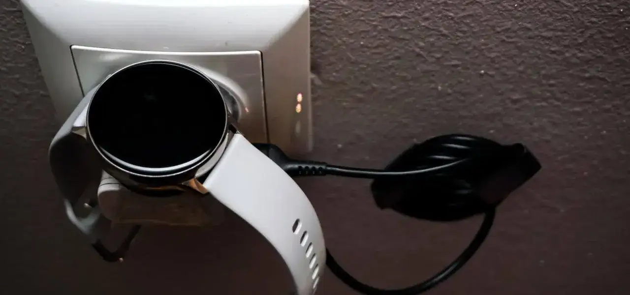 Biały smart bracelet podłączony do ładowarki w gniazdku. Dowiedz się, jak ładować swój smart bracelet.