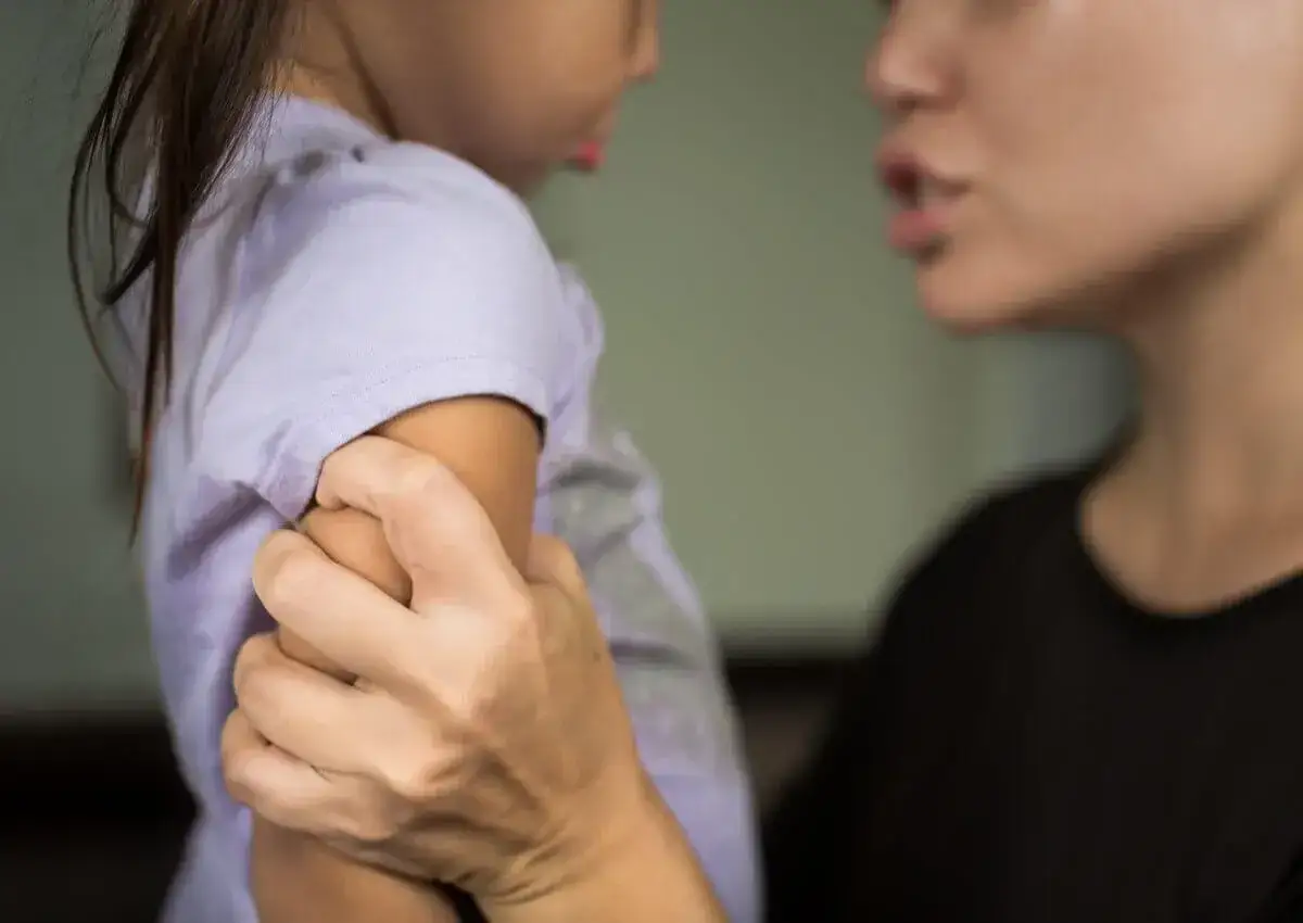 Eine Erzieherin h&auml;lt ein Kind am Arm fest, w&auml;hrend sie mit ihm spricht.