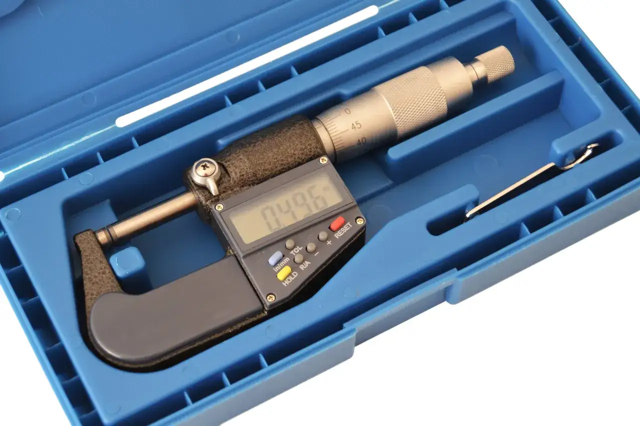 Micrómetro digital en su estuche azul, listo para mediciones precisas. Muestra 0.496.