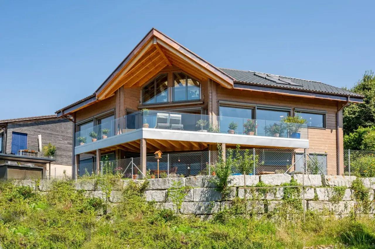 Modernes Holzhaus mit Glasbalkonen und einem auffälligen Satteldach, das neu interpretiert wurde.