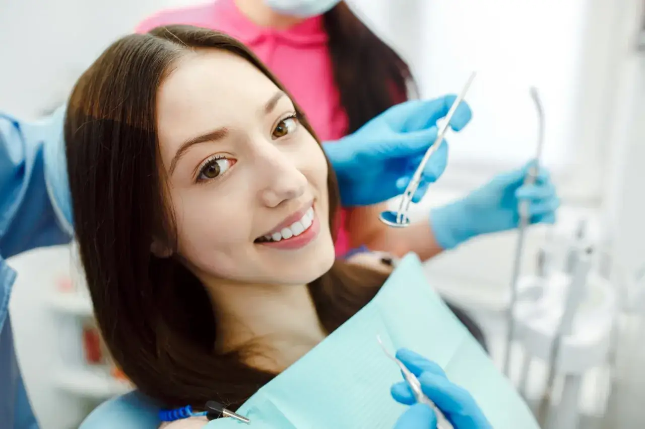 Uśmiechnięta pacjentka u dentysty, przygotowująca się do zabiegu z użyciem aparatu lingwalnego.