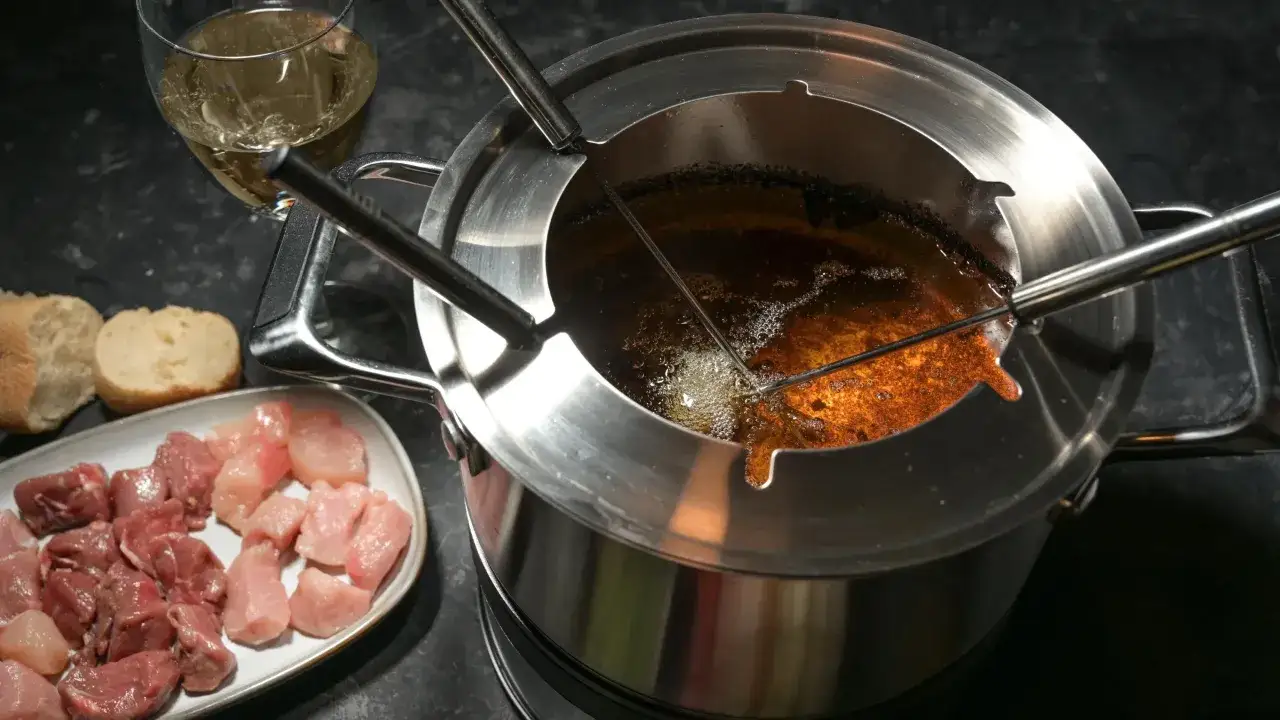 Préparation d'une fondue bourguignonne avec de la viande blanche et du pain. Le caquelon bouillonne, prêt à cuire les morceaux.