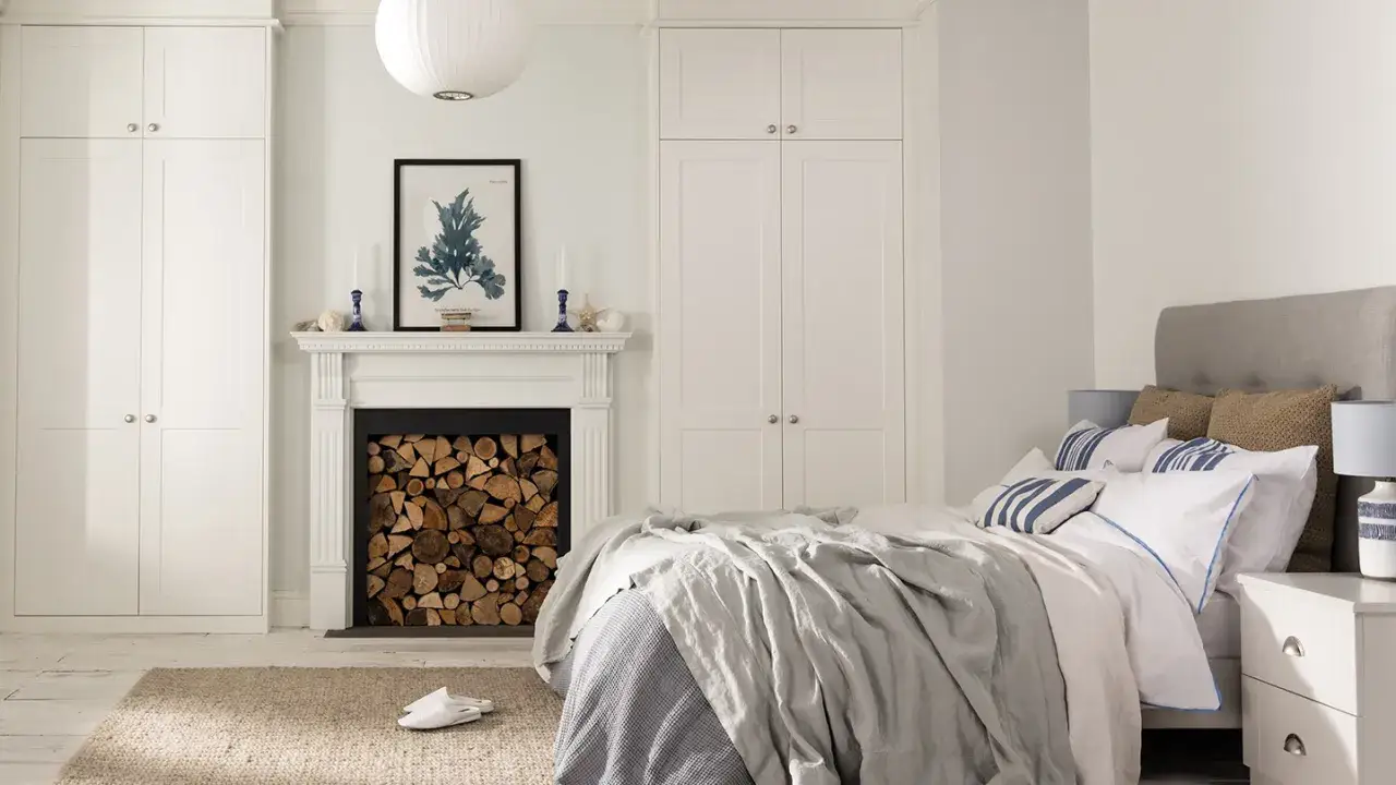 Serene guest room decor with a fireplace, stacked logs, and a cozy bed.