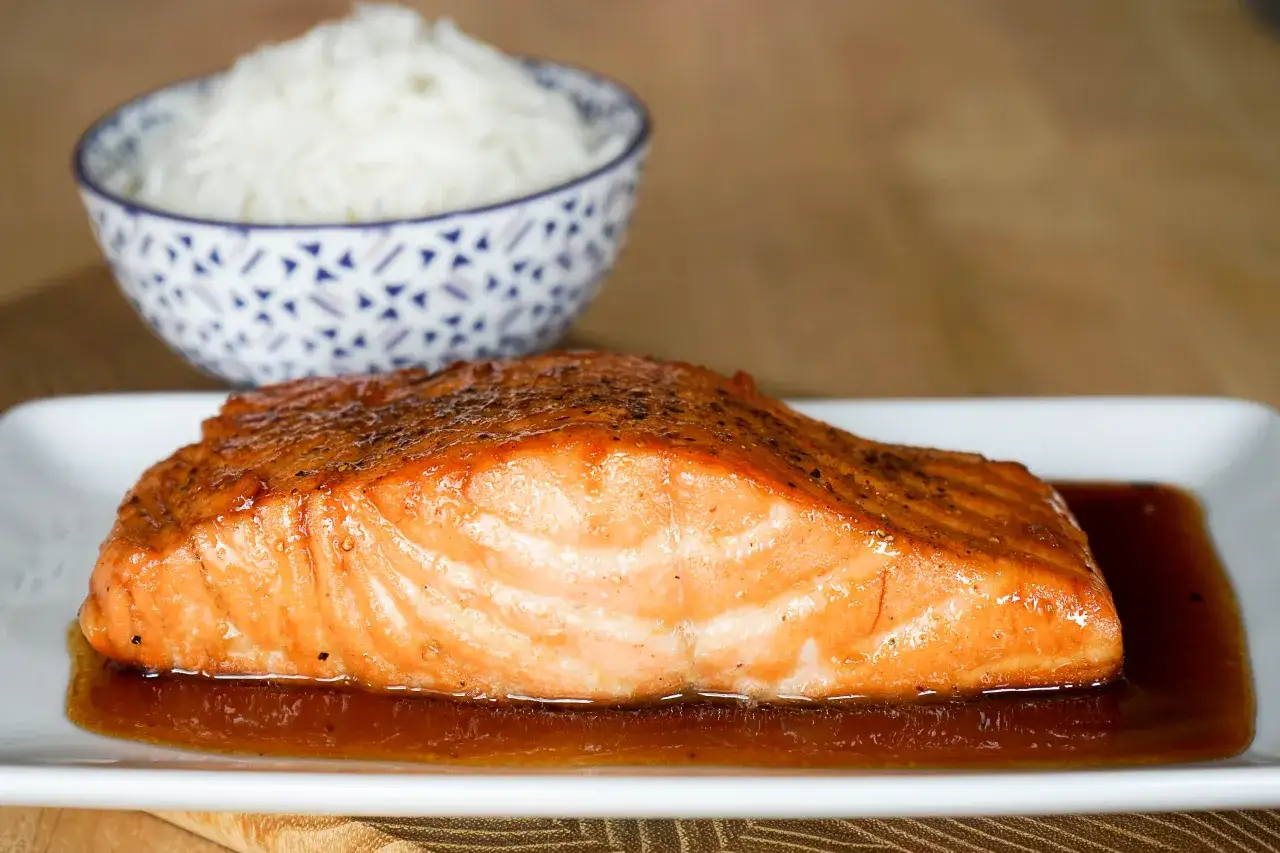 Un délicieux saumon sauce soja sucrée, laqué et brillant, servi avec du riz blanc dans un bol orné.