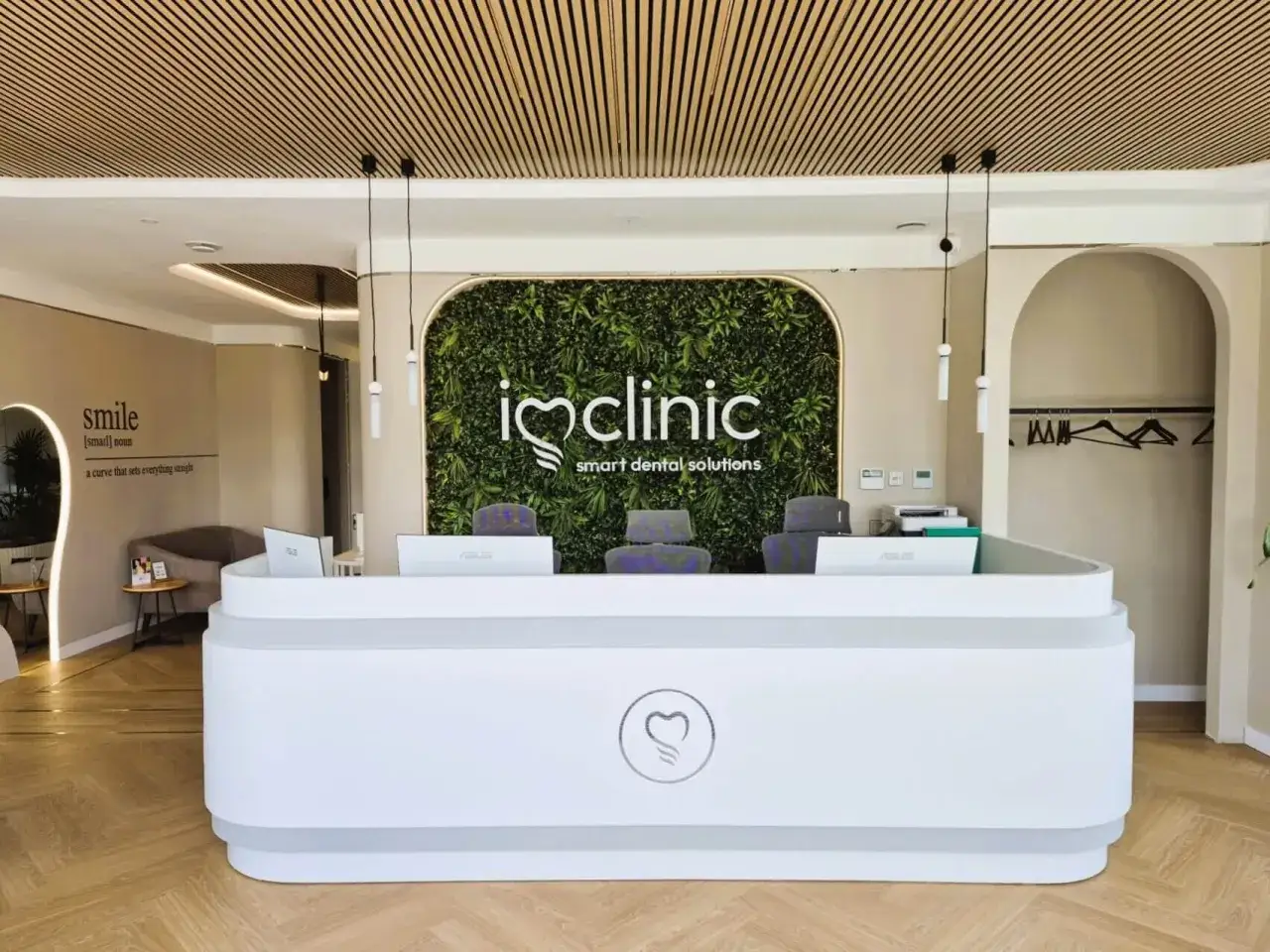 Recepcja kliniki stomatologicznej z zieloną ścianą i logo