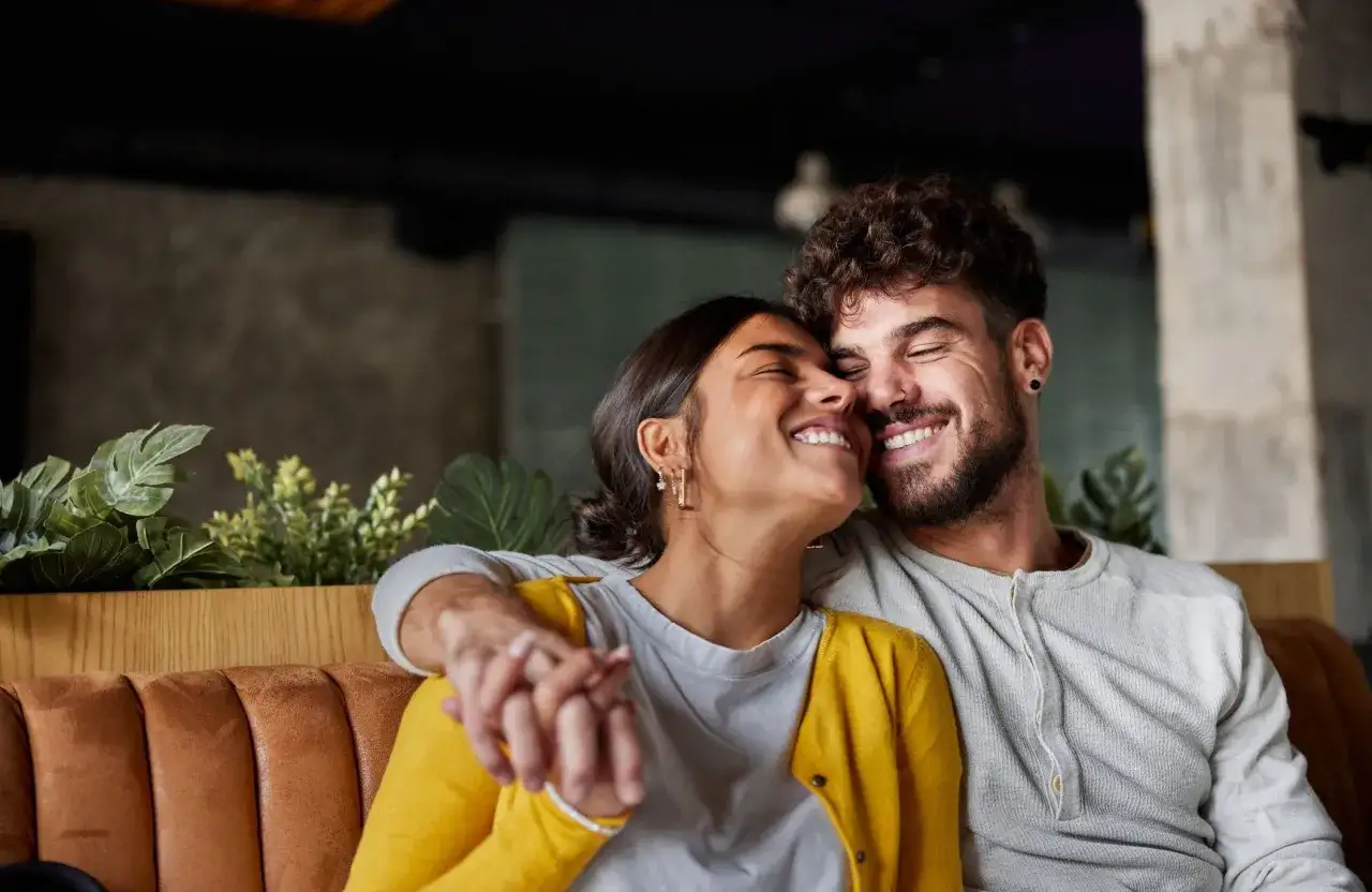 Un couple rayonnant de bonheur, main dans la main, partageant un moment de complicité. Leurs sourires radieux témoignent du vrai amour dans un couple.