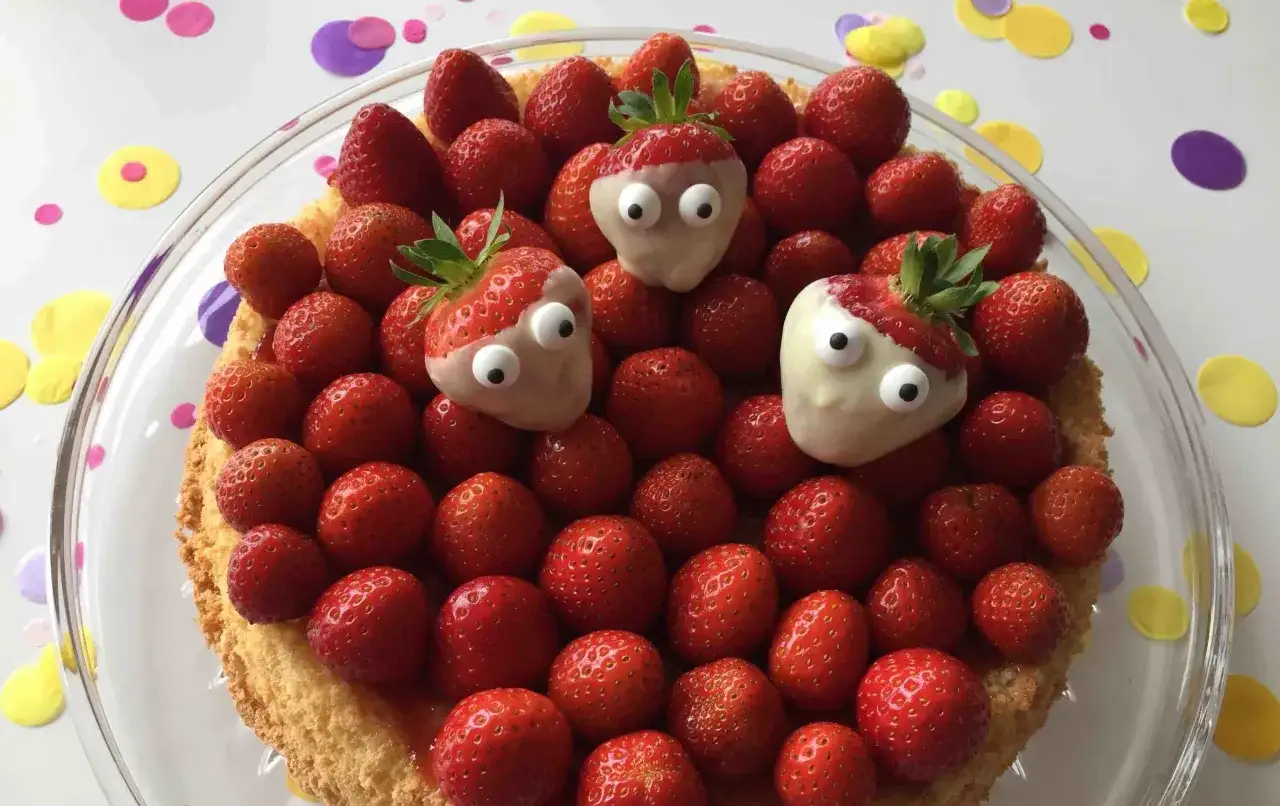 Ein leckerer Obstboden mit vielen frischen Erdbeeren, drei davon mit weißen Schokoladenaugen, die wie kleine Monster aussehen. Ein tolles Rezept für Kinder!