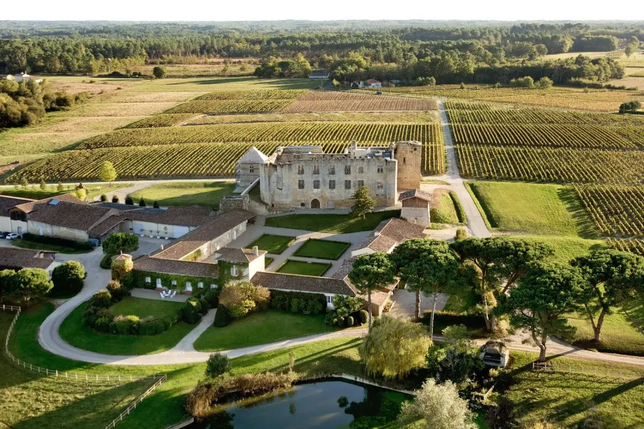 Château de Cazeneuve, propriété d'Alexandre de Lur Saluces, entouré de vignobles et de verdure, sous un ciel clair.