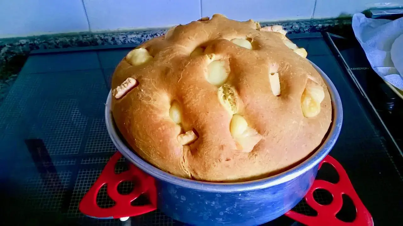 Pizza al formaggio marchigiana appena sfornata, dorata e soffice, con pezzi di formaggio filante che spuntano dall'impasto.
