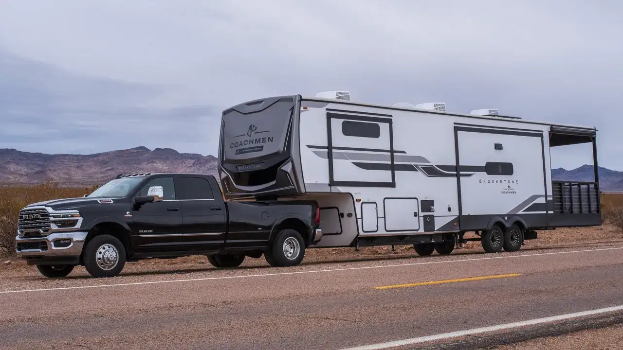 Czarny Dodge Ram 3500 z przyczepą kempingową Brookstone na pustynnej drodze.