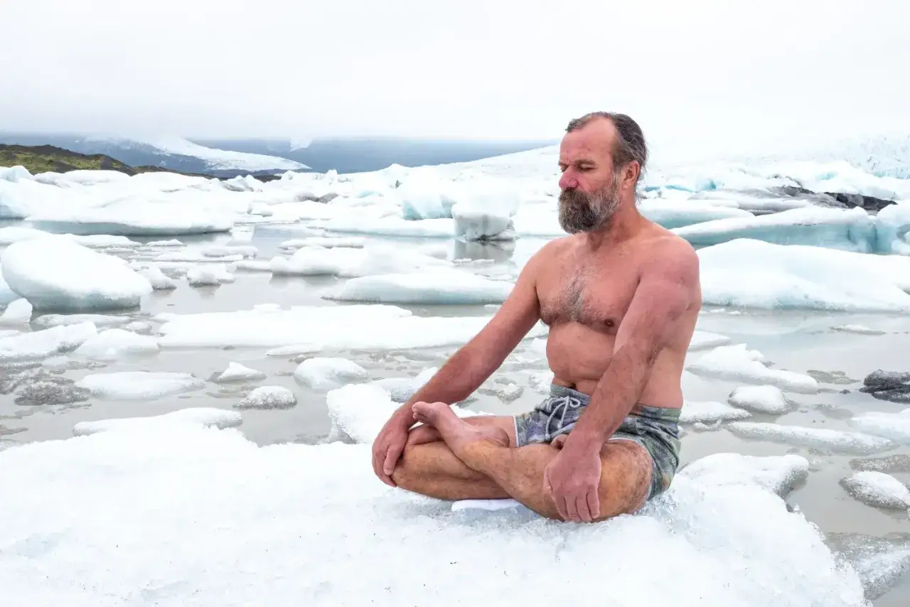 Wim Hof medytuje na lodzie w lodowatej wodzie, otoczony górami lodowymi.
