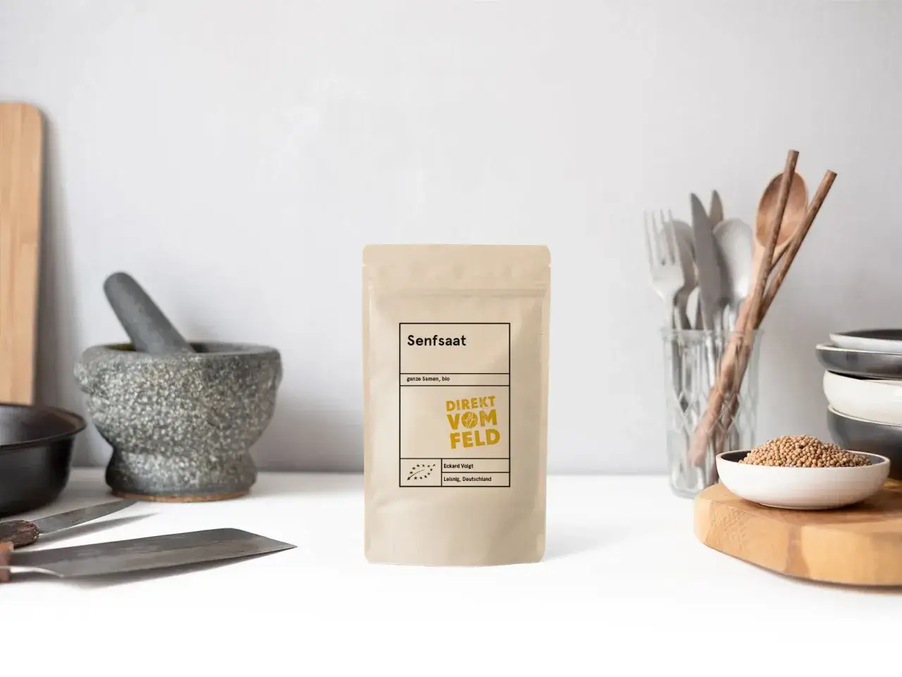 Senfsaat-Tüte neben Mörser und Schüssel mit Senfkörnern. Perfekt für Senfsaat Rezepte.