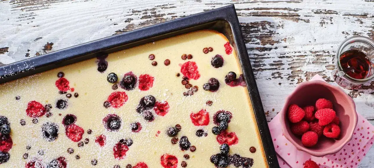 Frisch gebackener Ofenpfannkuchen mit Beeren und Puderzucker. Ein köstliches Rezept für süße Momente.