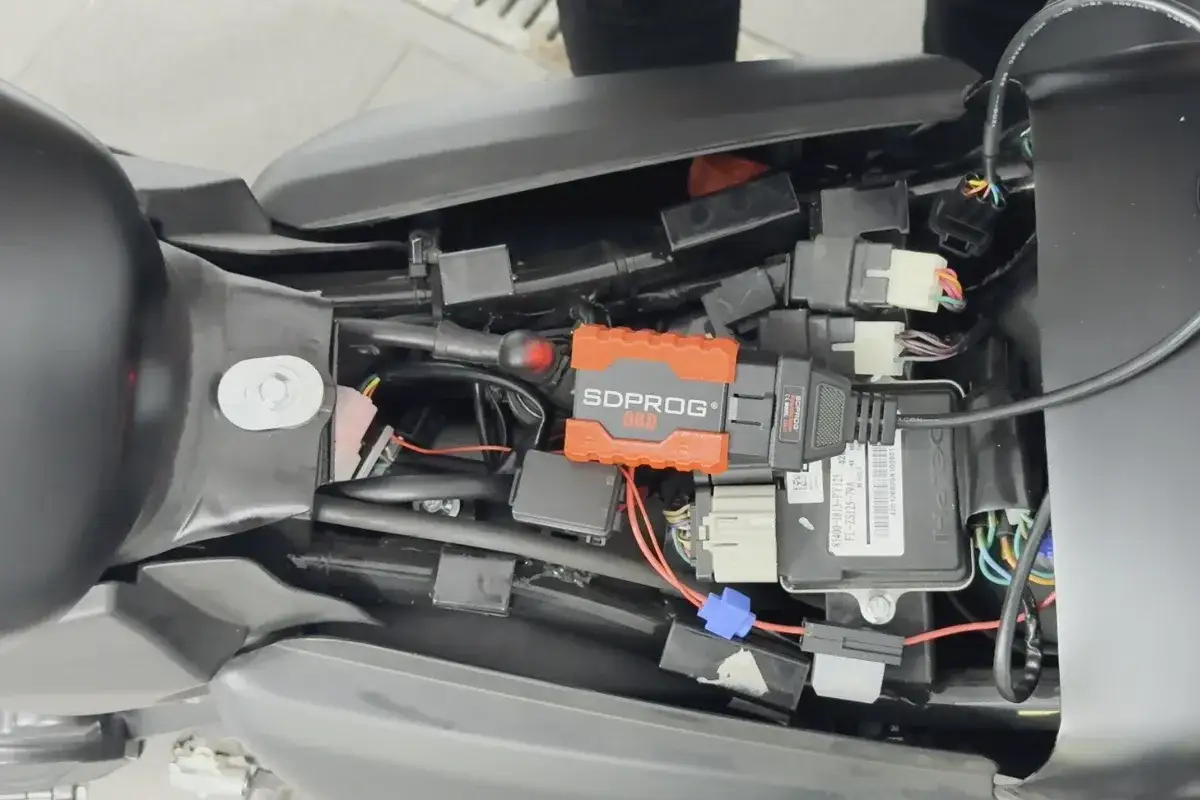 Pomarańczowe urządzenie SDPROG OBD podłączone do instalacji motocykla. Jaki przebieg dla motocykla jest duży? To zależy od wielu czynników.