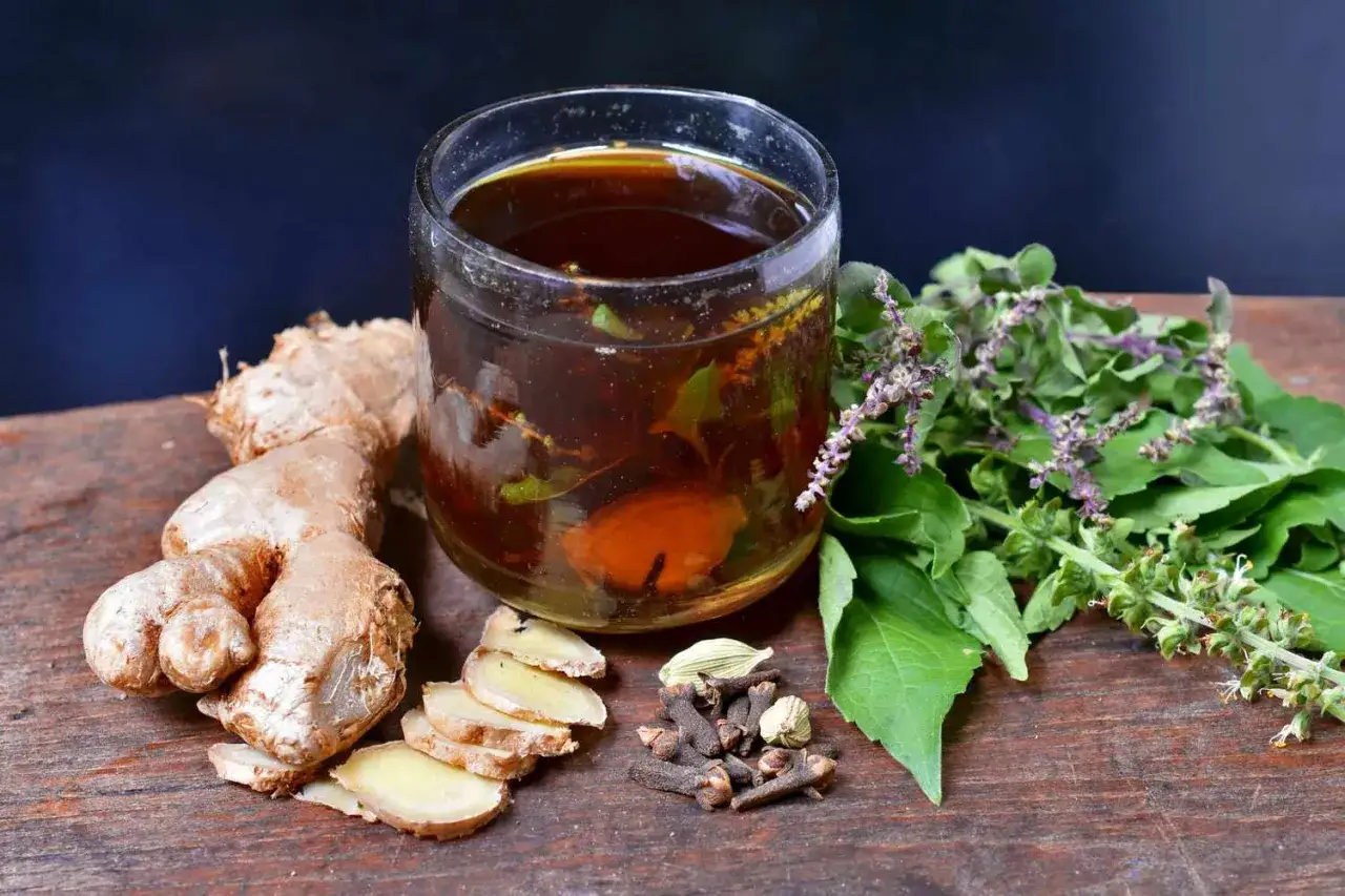 Verre de tisane anti inflammatoire aux épices et herbes fraîches, gingembre, clous de girofle, cardamome.