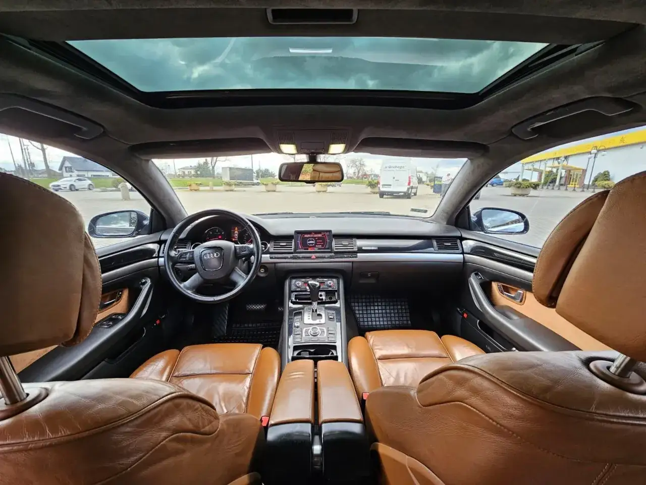 Wnętrze Audi A8 D2 4.2 z brązową skórzaną tapicerką i panoramicznym dachem.