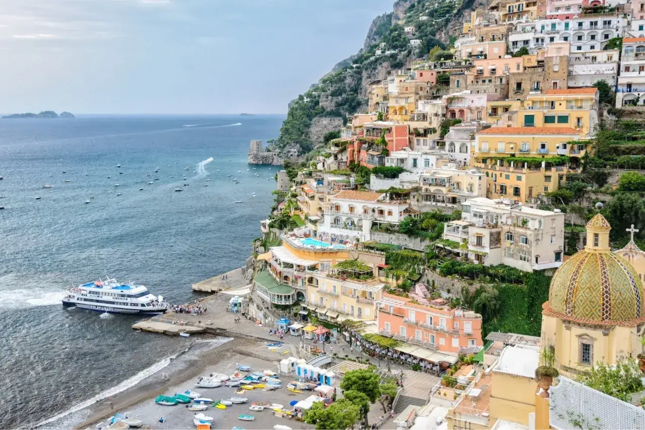 Widok na Positano, miasteczko na klifie, z łodzią przy brzegu i widokiem na morze w kierunku Capri.