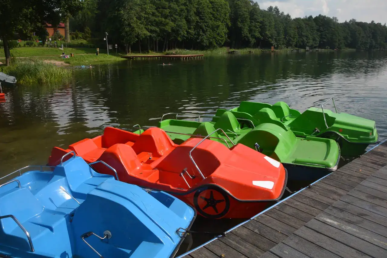 Kolorowe rowerki wodne czekają na gości na polu namiotowym nad Jeziorem Powidzkim.