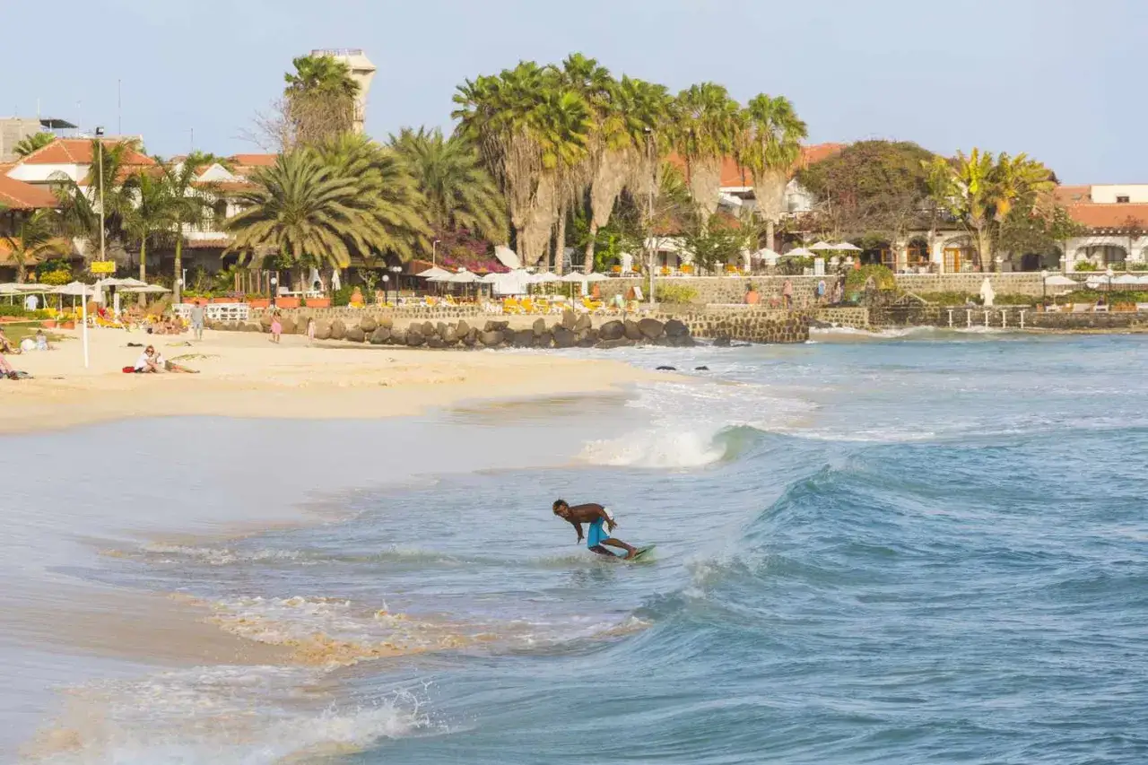 Surfer na fali na plaży Wysp Zielonego Przylądka. Listopadowa pogoda idealna na wodne sporty i relaks.
