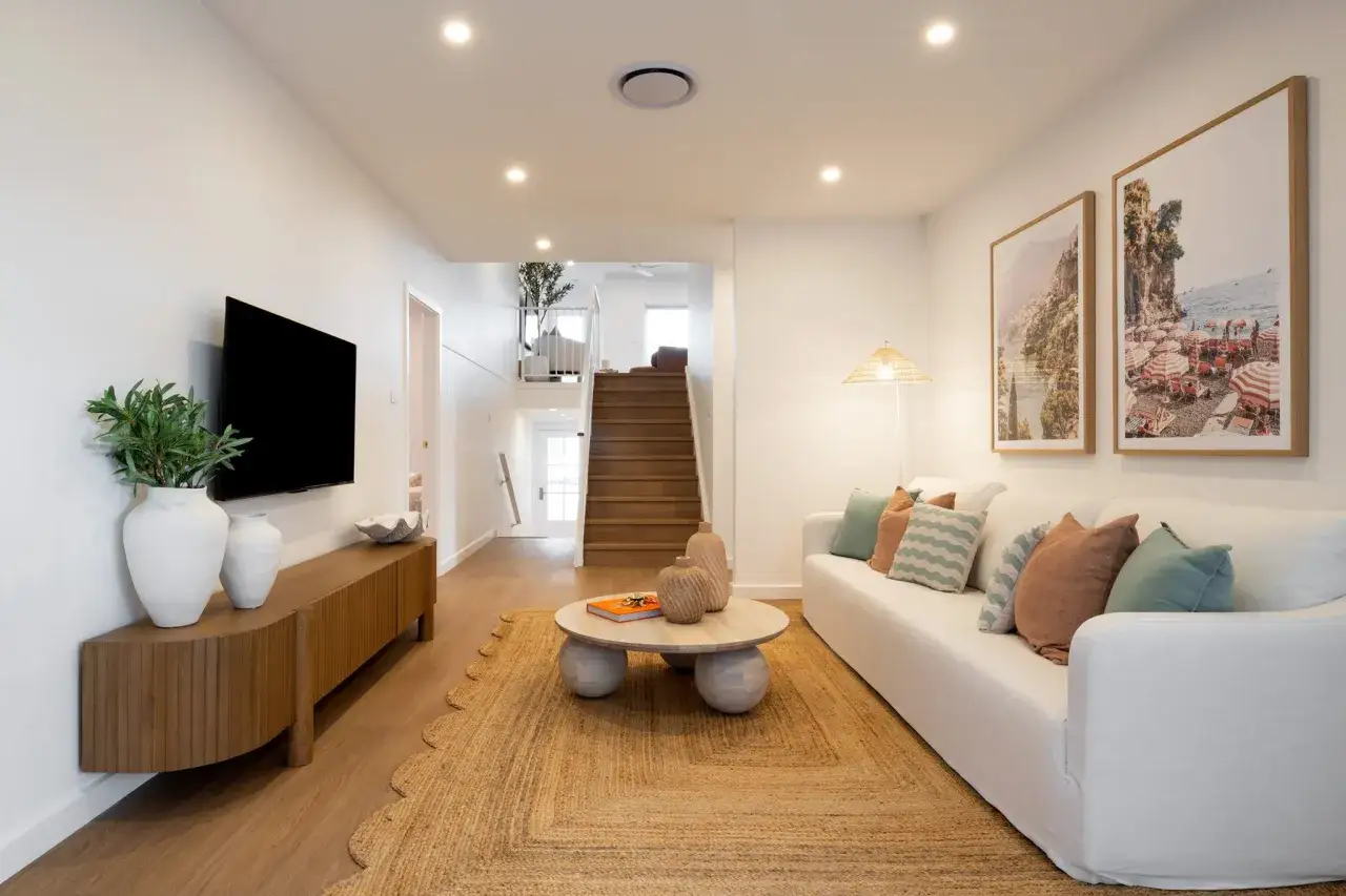 Living room of a split-level home with a white sofa, wooden media console, and stairs leading to an upper level.