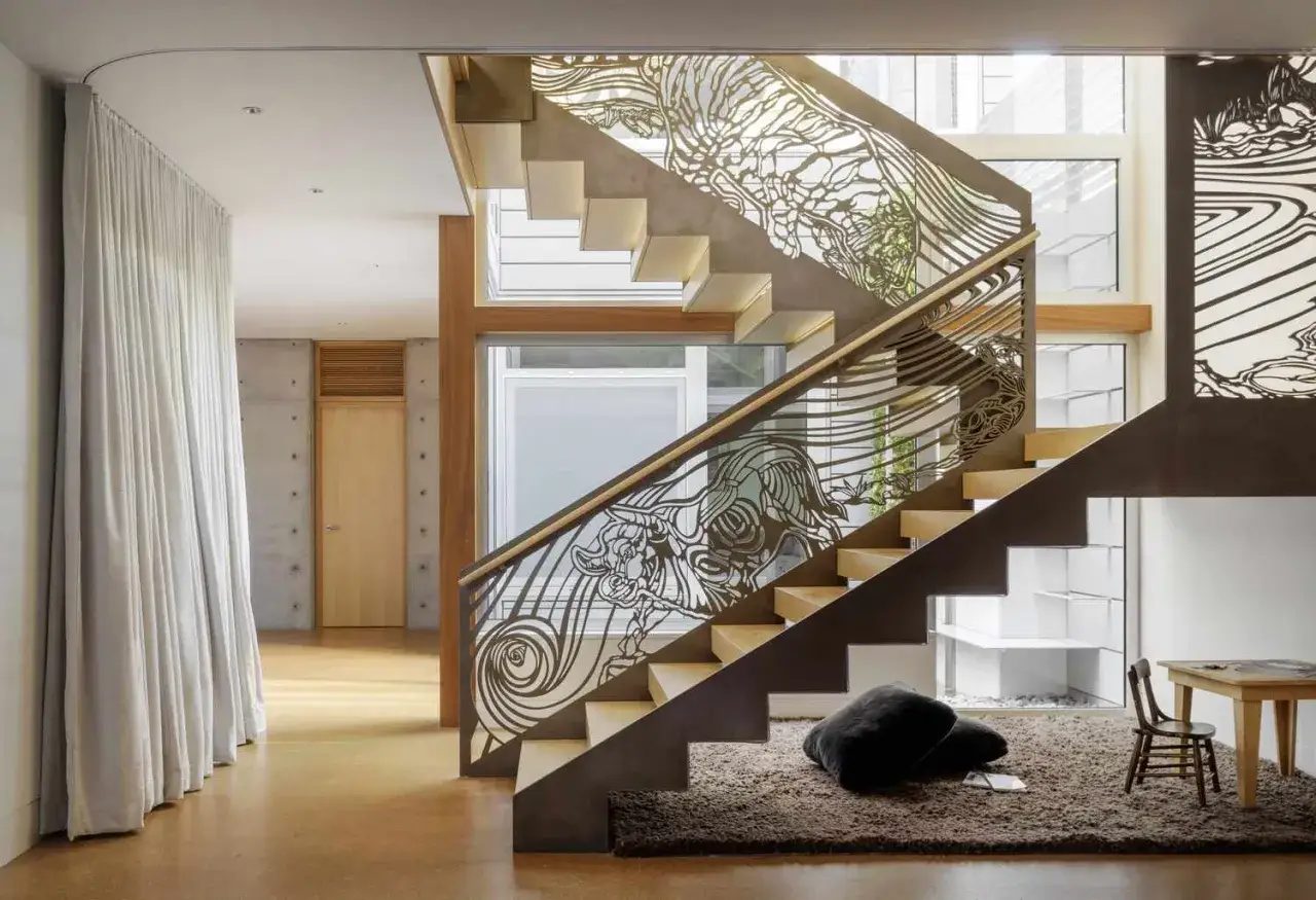 A modern staircase features a unique metal panel to replace stair railing, showcasing intricate designs of a bull and flowing water.
