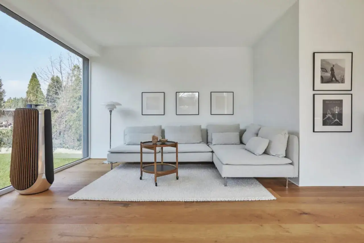 Moderne Wohnung einrichten Ideen: Helles Wohnzimmer mit gro&szlig;em Fenster, beigem Sofa, Holztisch und stilvollem Lautsprecher.
