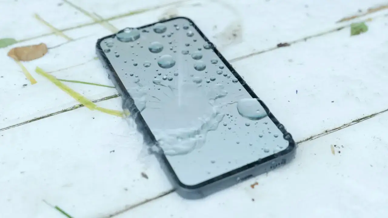 Smartfon z kroplami wody na ekranie. To dowód, że IP68 co oznacza ochronę przed zanurzeniem w wodzie, jest kluczowe dla Twojego urządzenia.