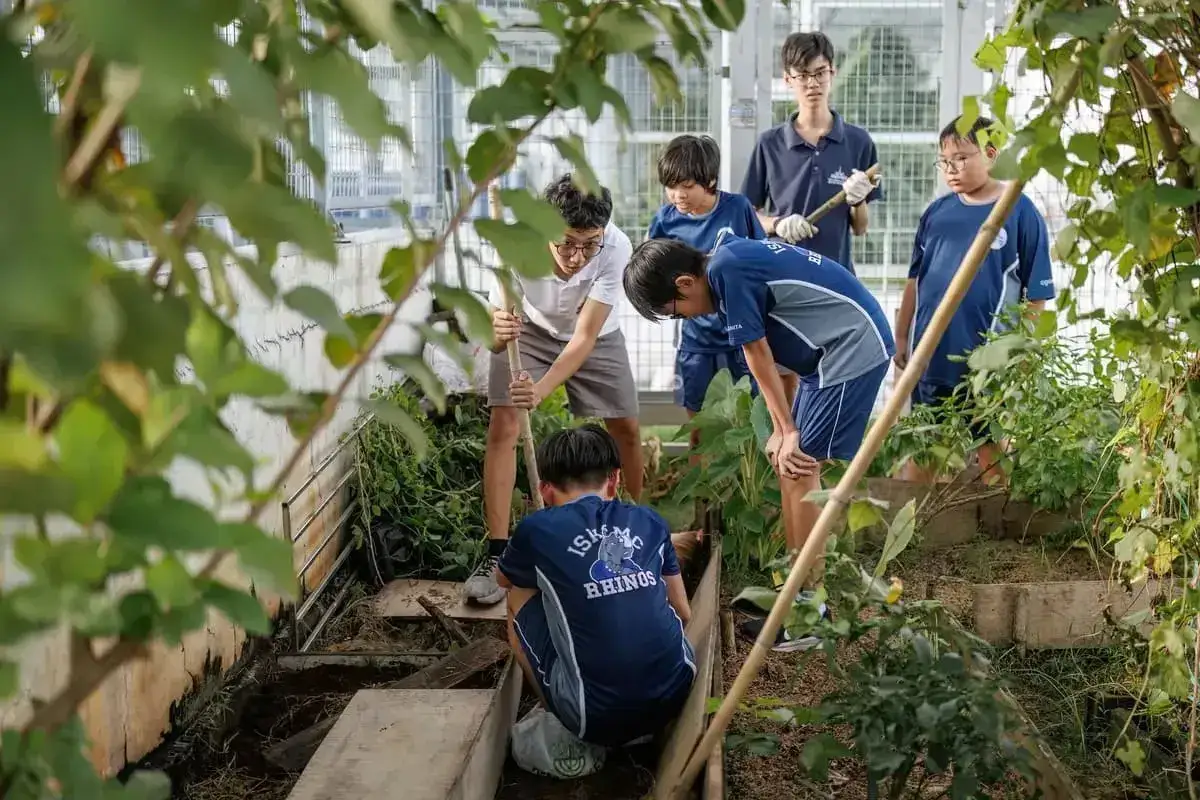 Jungen arbeiten in einem Gewächshaus an Nachhaltigkeitsprojekten mit Kindern. Sie graben und pflanzen, um die Umwelt zu schützen.