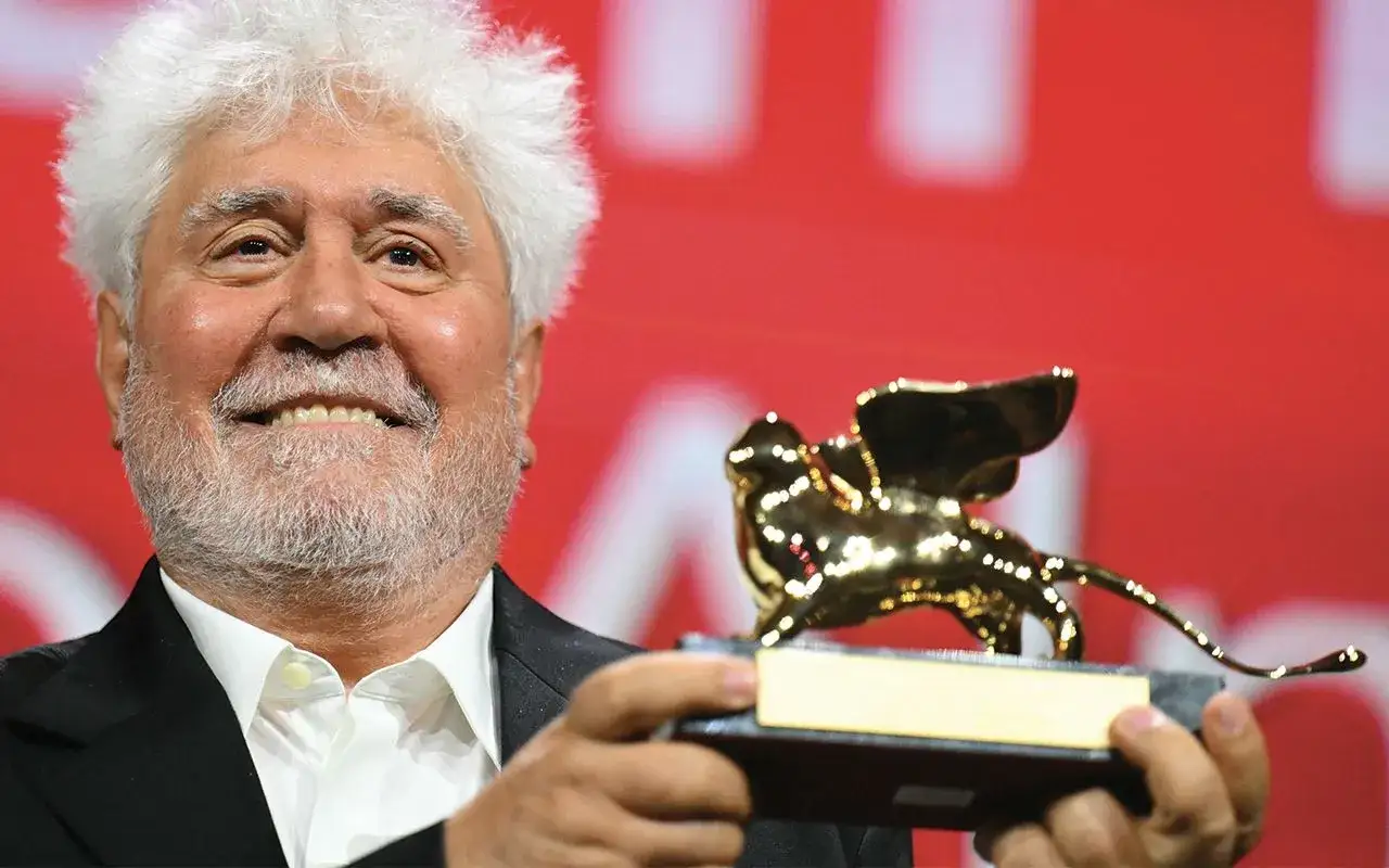 Un uomo sorride tenendo un leone d'oro, simbolo dei vincitori e candidati del festival.