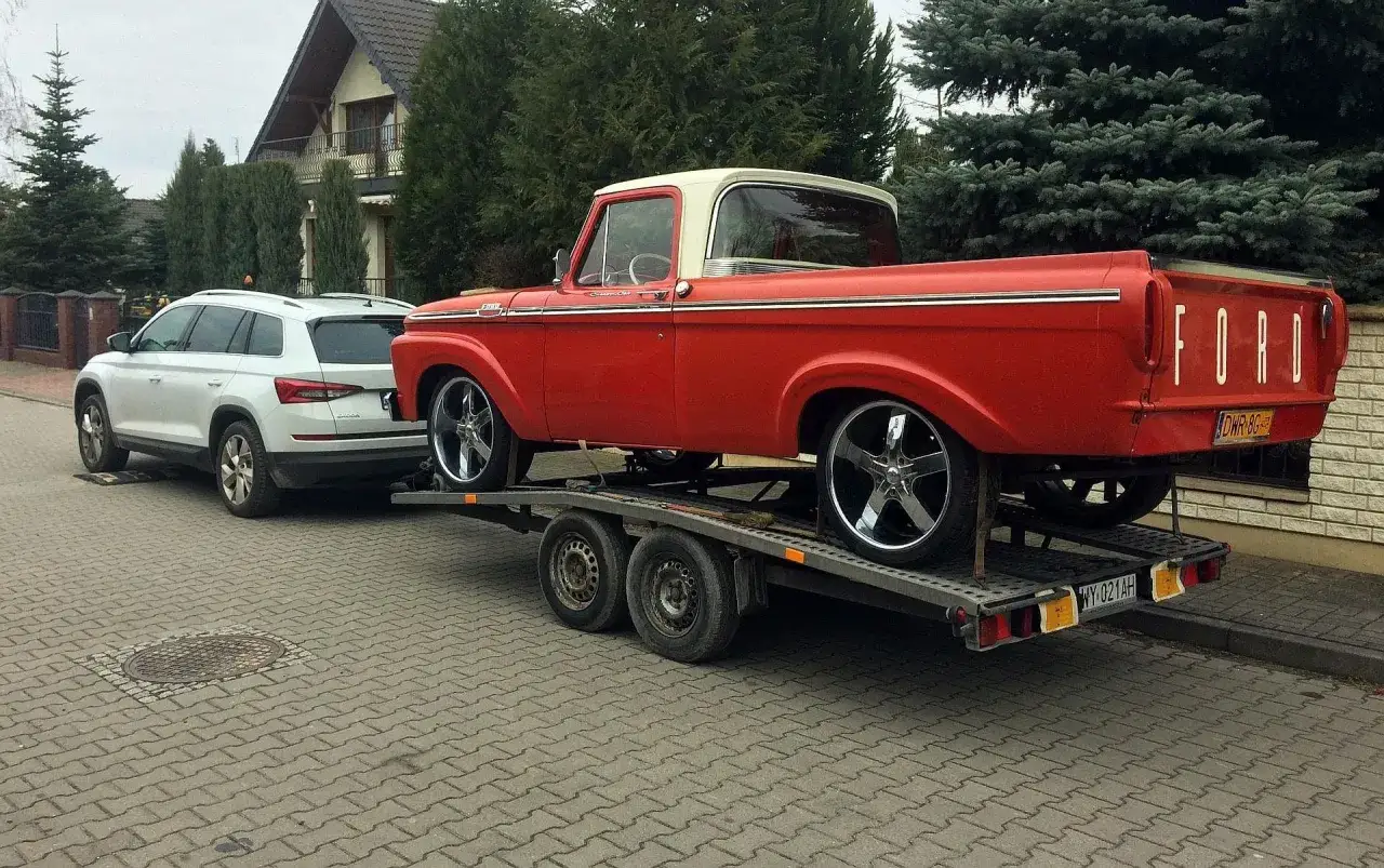 Czerwony Ford na lawecie, ciągnięty przez Skodę. Zastanawiasz się, ile kosztuje prawo jazdy na lawetę?