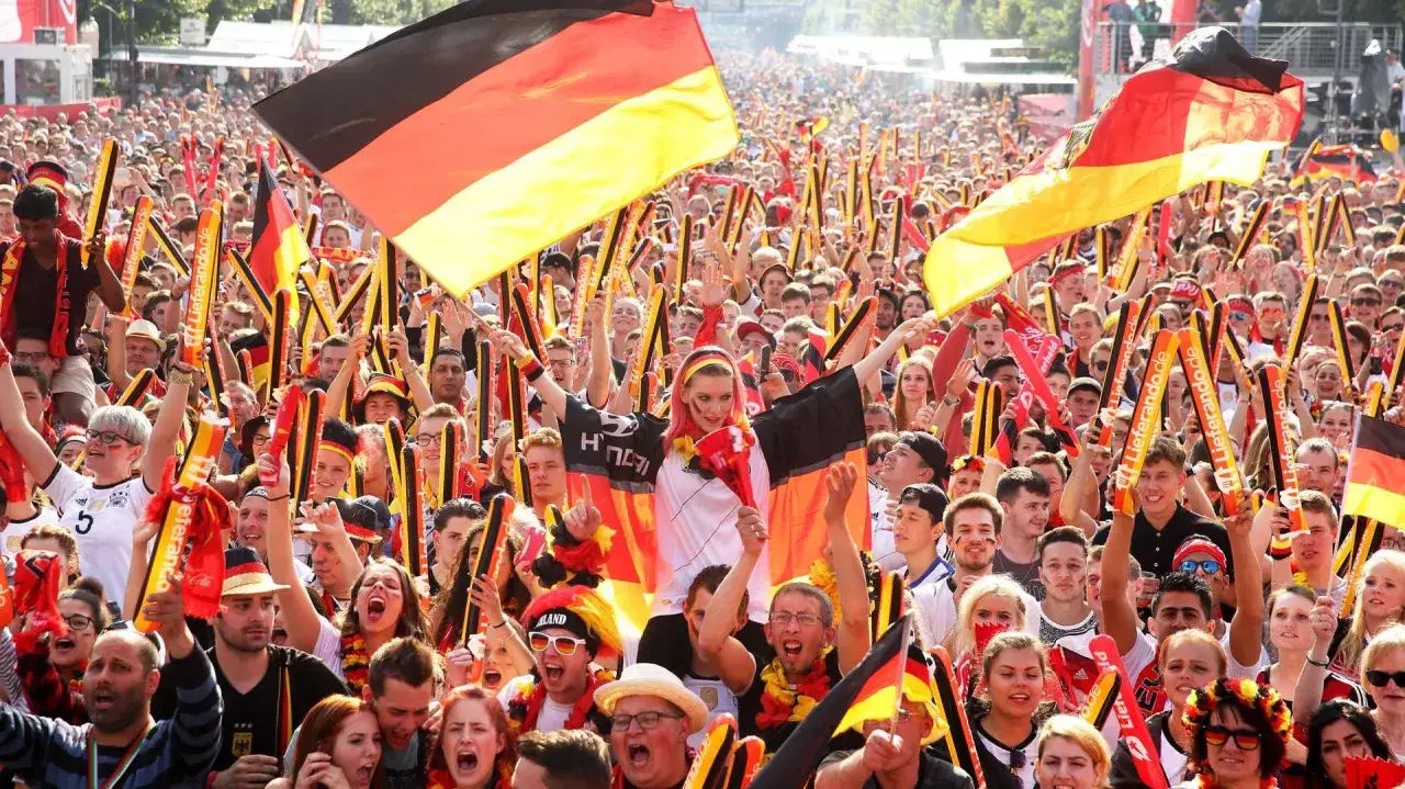 Eine jubelnde Menge mit Deutschlandflaggen und Fangesängen, ein Ausdruck von Nationalismus, der die Einheit und Leidenschaft für das Land zeigt.