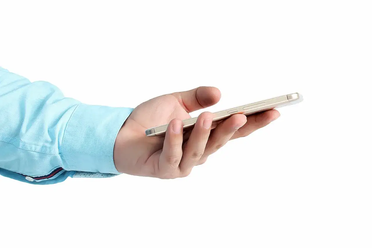 Dłoń trzymająca smartfon. Zastanawiasz się, kiedy można przenieść numer do innej sieci?