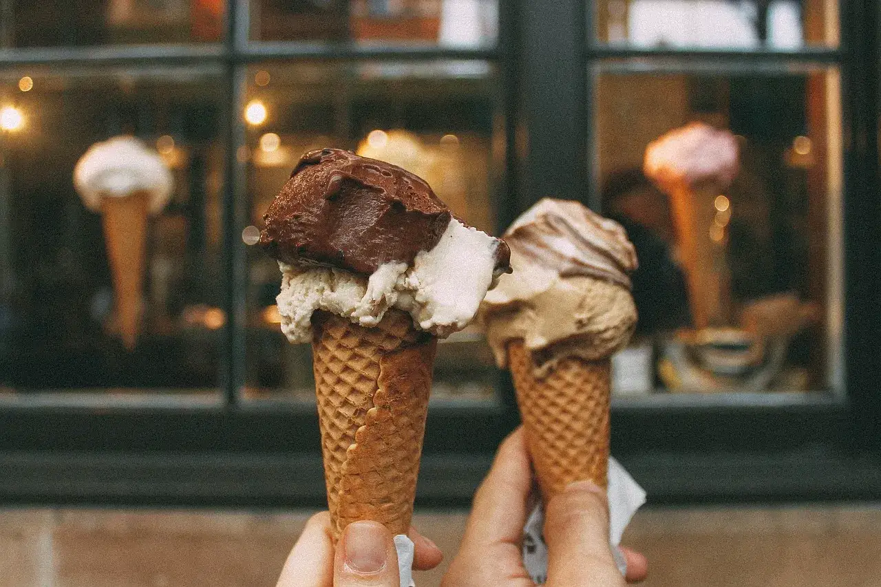 Due coni gelato, uno con cioccolato e crema, l'altro nocciola. Un assaggio della storia del gelato, un piacere che attraversa i secoli.