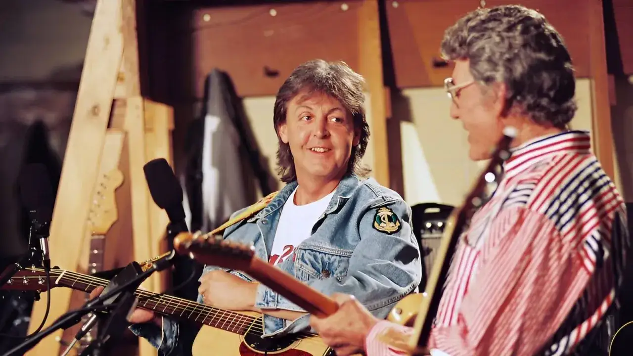 Zwei Musiker mit Gitarren, einer im Jeansjackett, der andere im gestreiften Hemd, scheinen sich über Musik zu unterhalten, als wären sie back in the USSR.