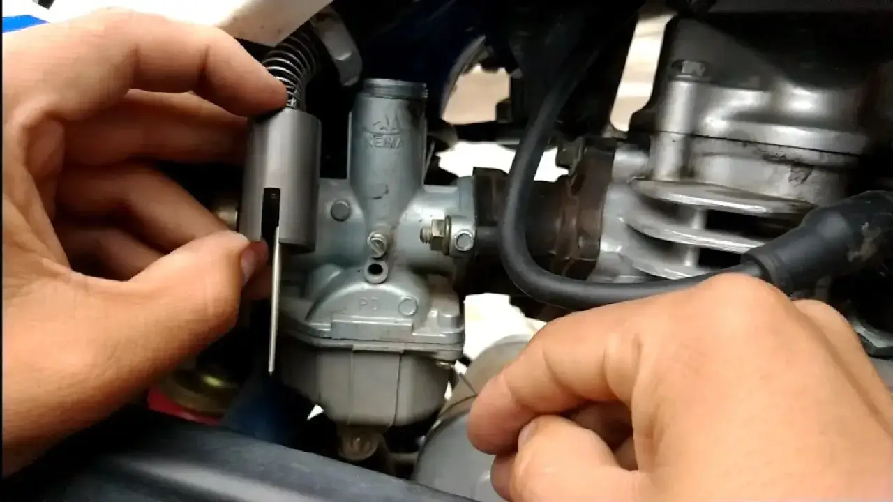 Mano ajustando el carburador de una moto, un paso clave para saber como desahogar una moto y optimizar su rendimiento.