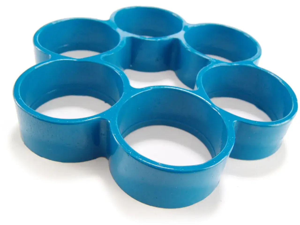 A blue, six-ringed object, likely a mold for compression molding materials, sits on a white surface.
