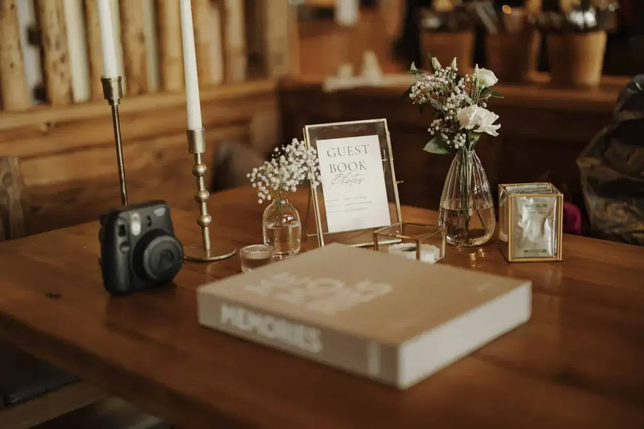 G&auml;stebuch, Sofortbildkamera und Blumenarrangements f&uuml;r originelle Ideen Hochzeit. Ein Tisch voller Erinnerungen.