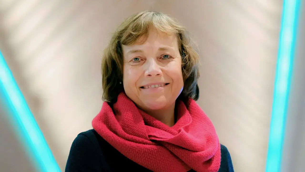 L&auml;chelnde Frau mit rotem Schal, die als EKD-Vorsitzende bekannt ist.