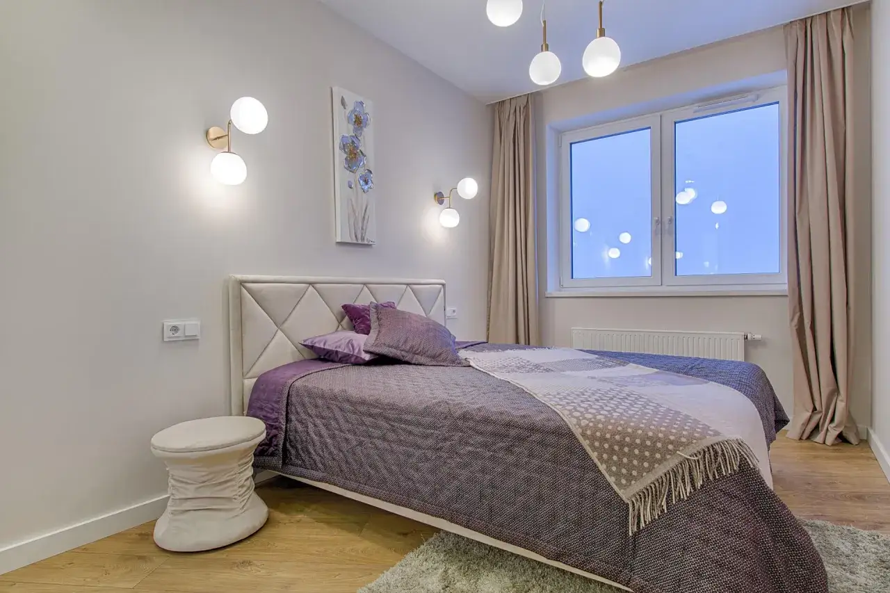 Elegancka narzuta na łóżko z subtelnym wzorem i ozdobnym kocem z frędzlami, podkreślająca różnicę między narzutą a kocem w dekoracji łóżka.