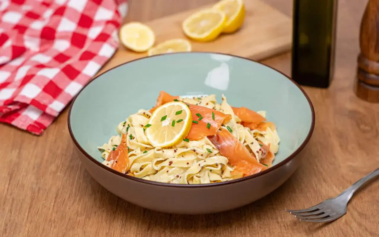 Un plat de tagliatelles au saumon, garni de rondelles de citron et de ciboulette, pr&ecirc;t &agrave; &ecirc;tre d&eacute;gust&eacute;.