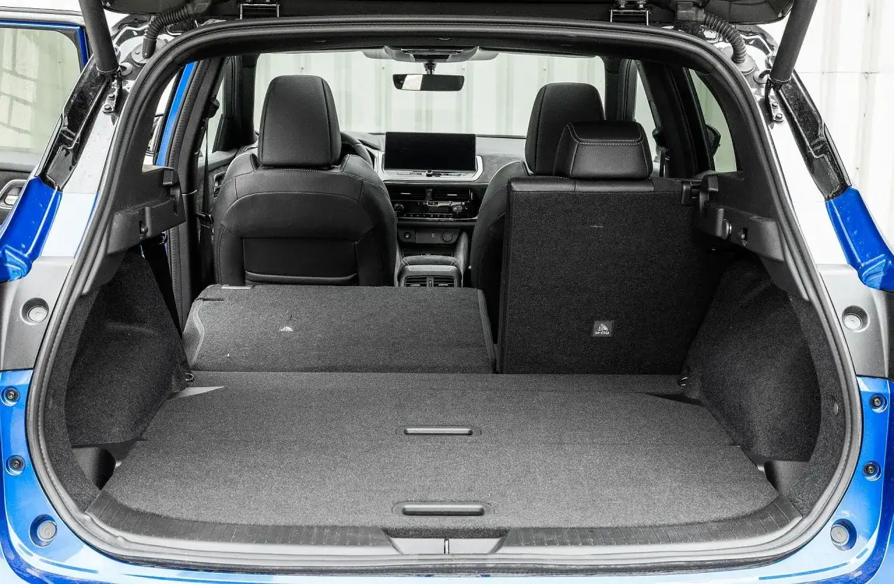 Wnętrze Nissana Qashqai 2023 z rozłożonymi tylnymi siedzeniami, tworzącymi dużą przestrzeń bagażową.