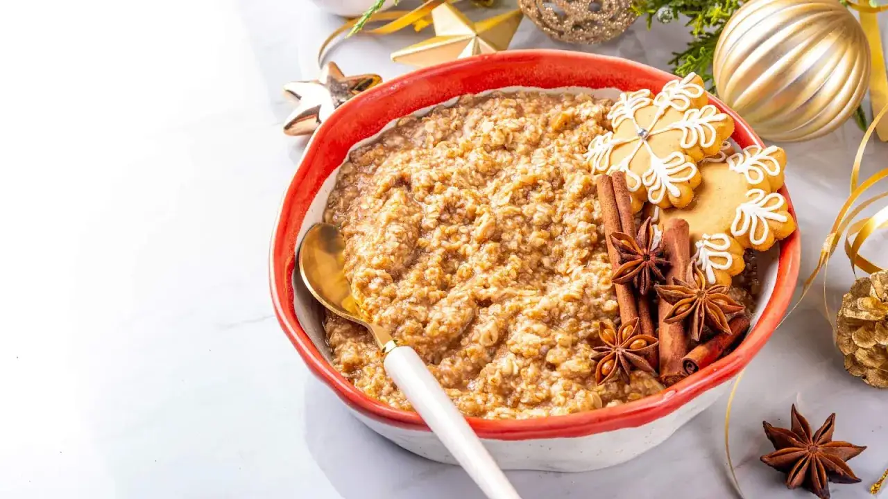 Herzhaftes Haferflocken-Porridge mit Lebkuchen-Flair, inspiriert von einem Lebkucheneis Rezept. Zimtstangen, Sternanis und Lebkuchen-Schneeflocken zieren die Schüssel.