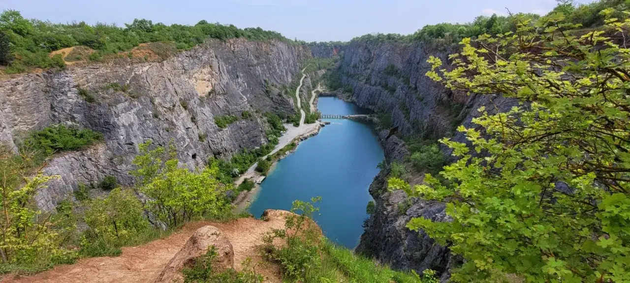 Ein atemberaubender Blick auf den Steinbruch Velká Amerika mit seinem tiefblauen Wasser, umgeben von steilen Felswänden und üppiger Vegetation.