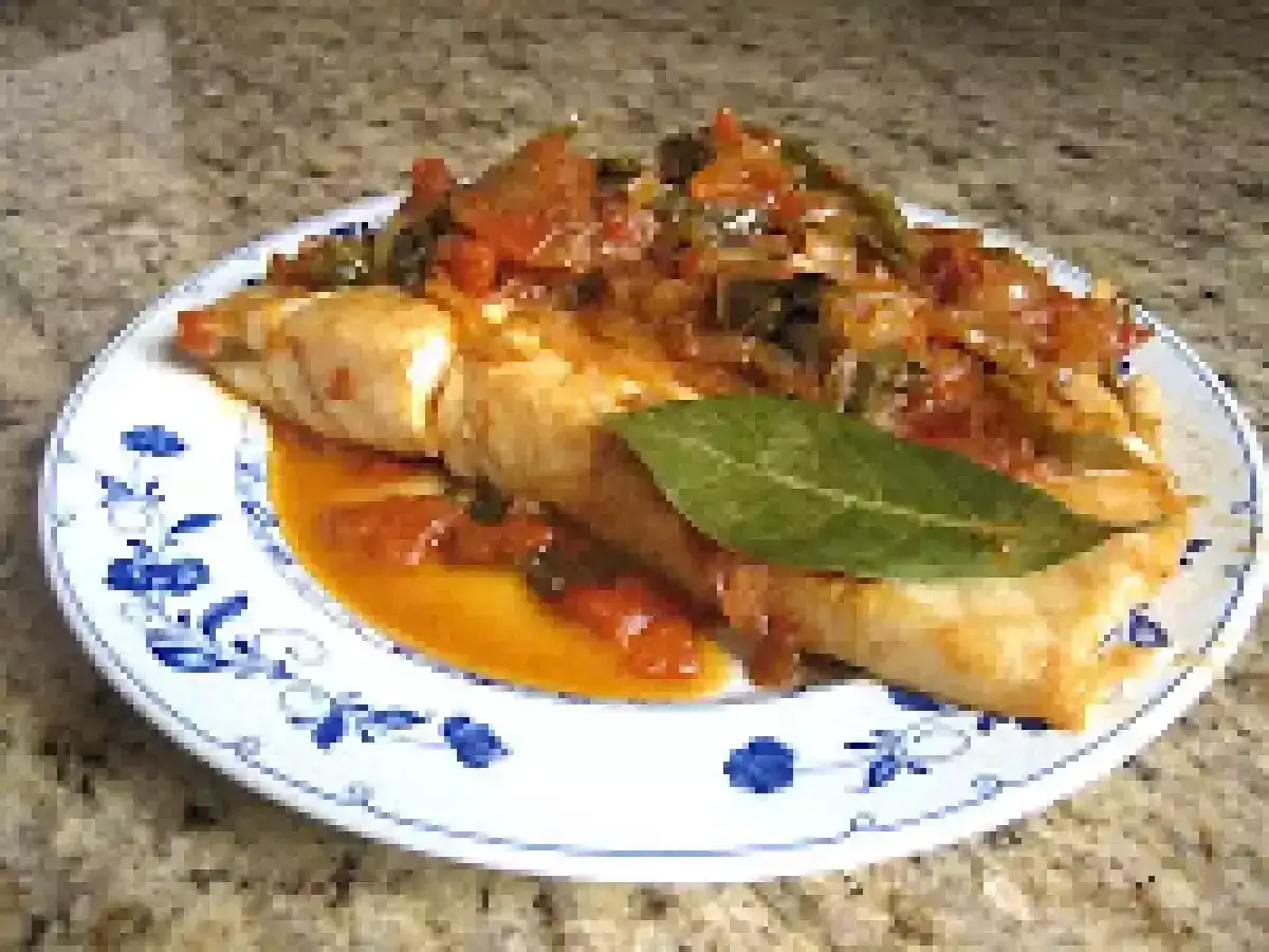 Deliciosa urta a la roteña, un plato de pescado con tomate y pimientos, adornado con una hoja de laurel.