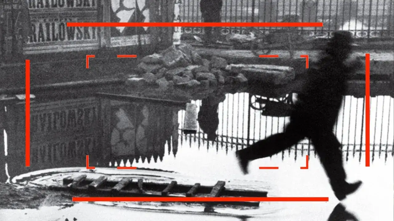 Un homme en chapeau court sur une flaque d'eau, reflet d'une scène urbaine. Une des henri cartier bresson photos célèbres.